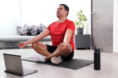 Koyu renk saçlı 40 yaşındaki Latin adam oturma odasında zihinsel, ruhsal ve fiziksel disiplin için online bir eğitmenle yoga yapıyor.