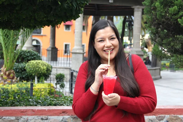 아메리카 의성인 여자는 곱슬곱슬 설탕물을 먹으면서 공원을 산책하면서 오후를 즐긴다 — 스톡 사진