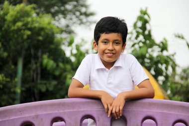 9 yaşındaki esmer tenli Latin çocuk yoksulluk içinde tatildeyken açık hava parkı oyunları oynuyor.