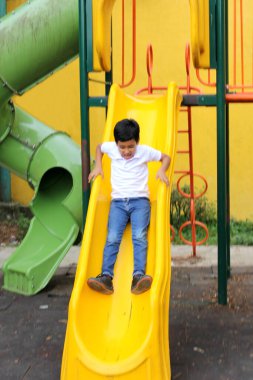 9 yaşındaki esmer tenli Latin çocuk yoksulluk içinde tatildeyken açık hava parkı oyunları oynuyor.