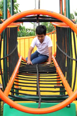 9 yaşındaki esmer tenli Latin çocuk yoksulluk içinde tatildeyken açık hava parkı oyunları oynuyor.