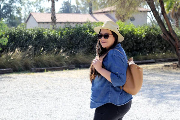 stock image Latin adult woman in a hat and sunglasses looks happy, explores on a hike to relax during her weekend break and summer vacation