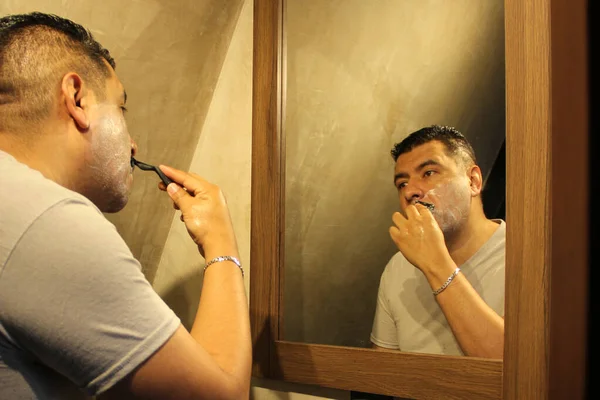 暗髪の40歳のラティーノの男性は 彼の美しさのルーチンを行い クリームと石鹸を剃って毛皮炎を避ける — ストック写真