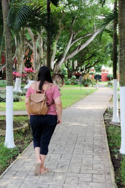 40 yaşında Latin bir kadın, Latin Amerika 'nın mutlu ve rahat bir şehrinin bahçesindeki kaldırımlı koloni sokaklarında huzur içinde güneşli bir günün tadını çıkarıyor.