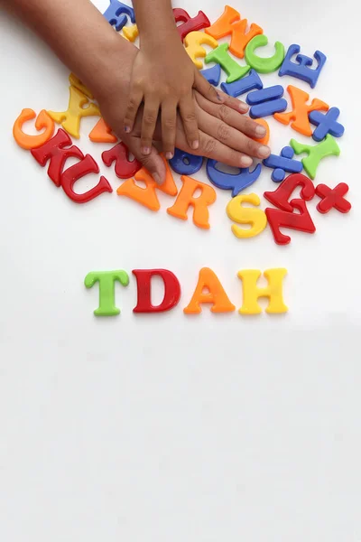 Hands of mom and daughter playing with colored letters that form ADHD Attention Deficit Hyperactivity Disorder in Spanish language