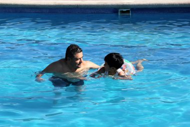 Boşanmış bekar bir baba ve 9 yaşındaki siyah saçlı bir çocuk havuzda birlikte yüzüyor yaz tatilinde ailece vakit geçiriyorlar.