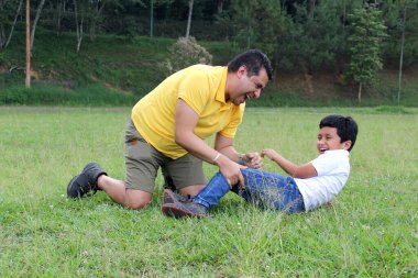 Boşanmış bekar baba ve 9 yaşındaki koyu renk saçlı Latin çocuk sahada eğleniyor ve Babalar Günü 'nü kutlamak için kaliteli zaman geçiriyorlar.