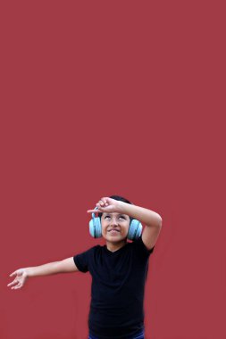 9 yaşındaki esmer tenli Latin çocuk kulaklıklarını dinliyor ve heyecanlı ve mutlu bir şekilde dans ederken müzik dinliyor.