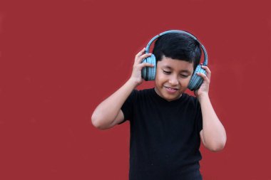 9 yaşındaki esmer tenli Latin çocuk kulaklıklarını dinliyor ve heyecanlı ve mutlu bir şekilde dans ederken müzik dinliyor.