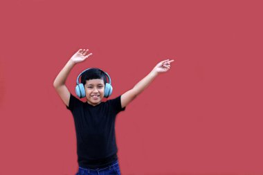 9 yaşındaki esmer tenli Latin çocuk kulaklıklarını dinliyor ve heyecanlı ve mutlu bir şekilde dans ederken müzik dinliyor.