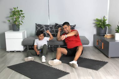 Şişman Latin baba ve oğlu, sağlıklarını iyileştirmek için evde yaptıkları egzersiz rekorunun kırılmasını kutluyorlar.