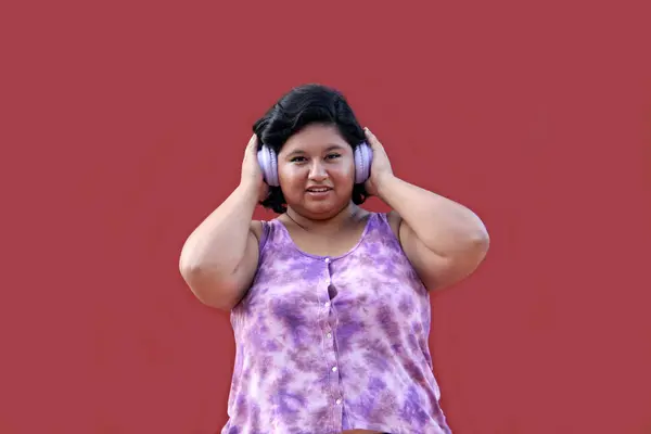 Young Latin woman of 20 years old fat brunette listens to music, podcasts and audiobooks with her headphones