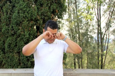 40 yaşındaki esmer tenli Latin adam alerji ve çevre kirliliği yüzünden acı çekiyor ve gözlerinde yanıklar var.