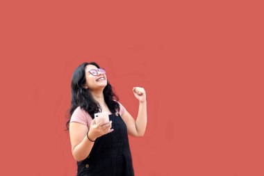 Gözlüklü ve parantezli esmer Latin kadın cep telefonunu mesaj atmak, alışveriş yapmak ve çıkmak için kullanıyor.