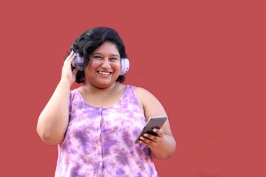 20 yaşındaki genç esmer ve şişman kadın müzik dinlemek için kulaklık kullanıyor, müzik listesi, podcastlar, sesli kitaplar.