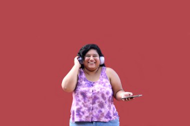 20 yaşındaki genç esmer ve şişman kadın müzik dinlemek için kulaklık kullanıyor, müzik listesi, podcastlar, sesli kitaplar.