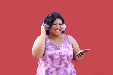 20 yaşındaki genç esmer ve şişman kadın müzik dinlemek için kulaklık kullanıyor, müzik listesi, podcastlar, sesli kitaplar.