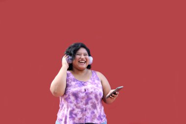 20 yaşındaki genç esmer ve şişman kadın müzik dinlemek için kulaklık kullanıyor, müzik listesi, podcastlar, sesli kitaplar.