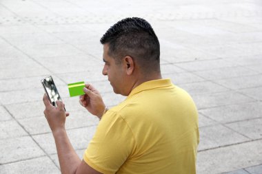 40 yaşında esmer tenli Latin bir adam kredi kartıyla sorun yaşıyor ve müşteri hizmetlerini arıyor.
