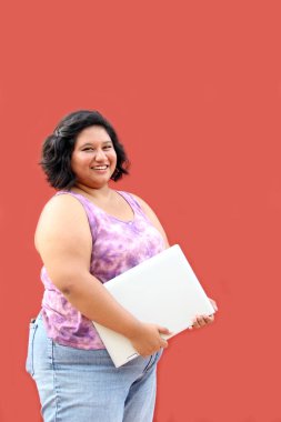 20 yaşında, şişman esmer bir kadın laptopunu ders çalışmak, ödevlerini yapmak, internetten alışveriş yapmak ve arkadaşlarıyla sohbet etmek için kullanıyor.