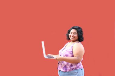 20 yaşında, şişman esmer bir kadın laptopunu ders çalışmak, ödevlerini yapmak, internetten alışveriş yapmak ve arkadaşlarıyla sohbet etmek için kullanıyor.