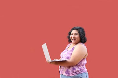 20 yaşında, şişman esmer bir kadın laptopunu ders çalışmak, ödevlerini yapmak, internetten alışveriş yapmak ve arkadaşlarıyla sohbet etmek için kullanıyor.