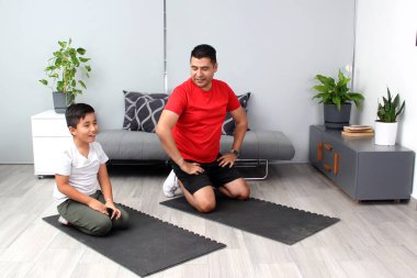 Latin baba ve oğul oturma odalarında egzersiz yapmaya hazırlanıyorlar. Kilo vermek, obeziteden kaçınmak ve aile sağlıklarını iyileştirmek için.