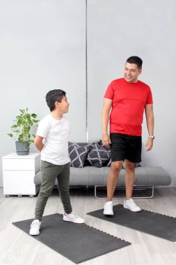 Latin baba ve oğul oturma odalarında egzersiz yapmaya hazırlanıyorlar. Kilo vermek, obeziteden kaçınmak ve aile sağlıklarını iyileştirmek için.