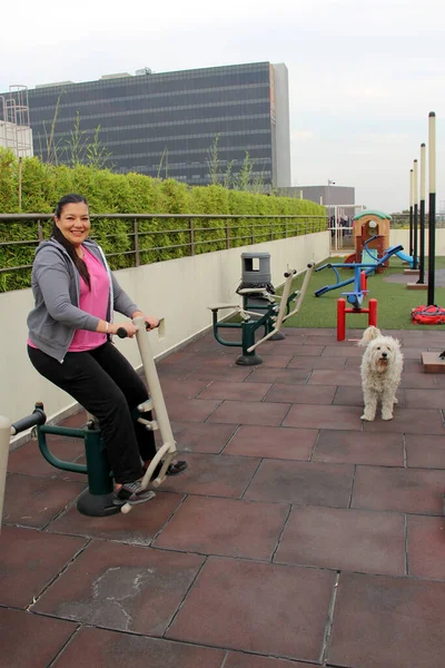 40-year-old Latina woman exercises in the roof garden of her condominium accompanied by her emotional support dog to overcome her depression and anxiety