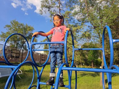 4 yaşındaki Latin esmer kız, güneşin altında ultraviyole ışınlarla korunma riskiyle oyun oynuyor.