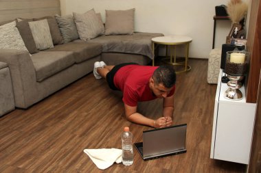 Kırk yaşında esmer tenli Latin adam, kırık ve ameliyat sonrası rehabilitasyonda kol ve bacakları güçlendirmek için şınav çekiyor.