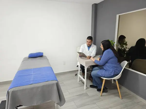 Dark-skinned male specialist doctor attends to female patient in consultation in his office for annual medical check-up