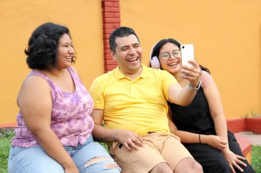 Boşanmış bekar baba ve koyu tenli Latin ergen kızları cep telefonuyla fotoğraf çekerek eğleniyorlar.