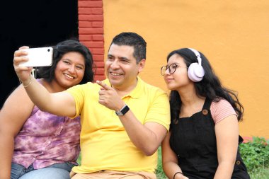 Boşanmış bekar baba ve koyu tenli Latin ergen kızları cep telefonuyla fotoğraf çekerek eğleniyorlar.