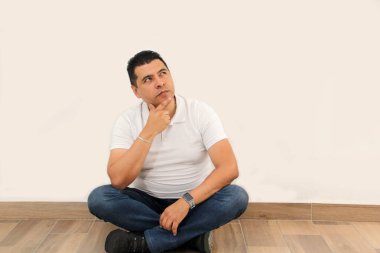 Koyu tenli Latin 40 yaşındaki adam terfi ve indirim mesajı için beyaz duvarı işaret ediyor.