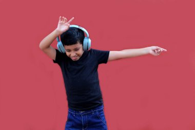 9 yaşındaki koyu tenli Latin çocuk kulaklıklarıyla müzik dinliyor ve heyecanla indirimlere ve promosyonlara işaret ediyor.