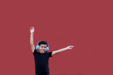 9 yaşındaki koyu tenli Latin çocuk kulaklıklarıyla müzik dinliyor ve heyecanla indirimlere ve promosyonlara işaret ediyor.