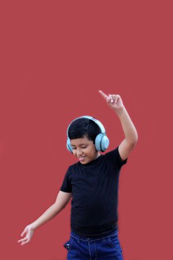 9 yaşındaki koyu tenli Latin çocuk kulaklıklarıyla müzik dinliyor ve heyecanla indirimlere ve promosyonlara işaret ediyor.