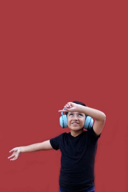 9 yaşındaki koyu tenli Latin çocuk kulaklıklarıyla müzik dinliyor ve heyecanla indirimlere ve promosyonlara işaret ediyor.
