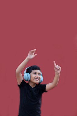 9 yaşındaki koyu tenli Latin çocuk kulaklıklarıyla müzik dinliyor ve heyecanla indirimlere ve promosyonlara işaret ediyor.