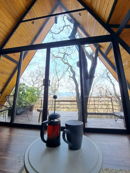 Preparing coffee in a French press or plunger coffee maker inside a cabin in the middle of the forest as a symbol of relaxation and luxury