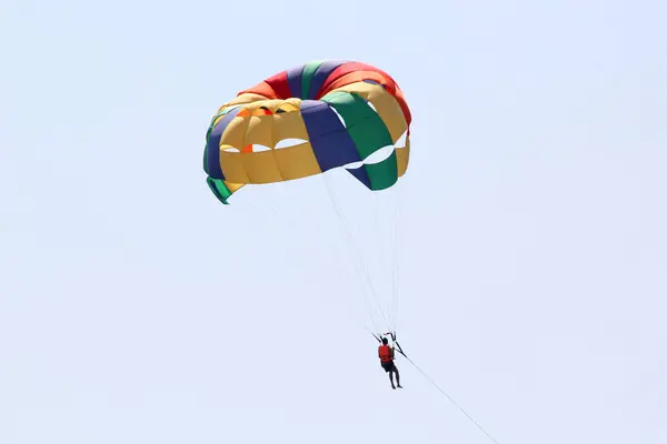 Parasailing, Parascending or Parakiting is an aquatic activity where a person attached to a parachute is towed by a boat at speed, causing them to rise above the water