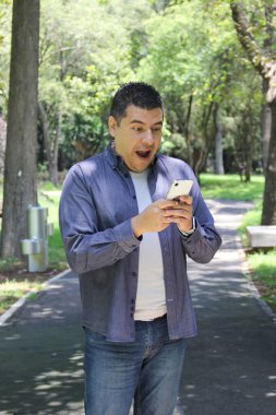 40 yaşında esmer tenli Latin bir adam cep telefonuyla video görüşmeleri yapıyor, mesajlar gönderiyor, ödeme yapıyor, alışveriş yapıyor ve uzaktan çalışıyor.