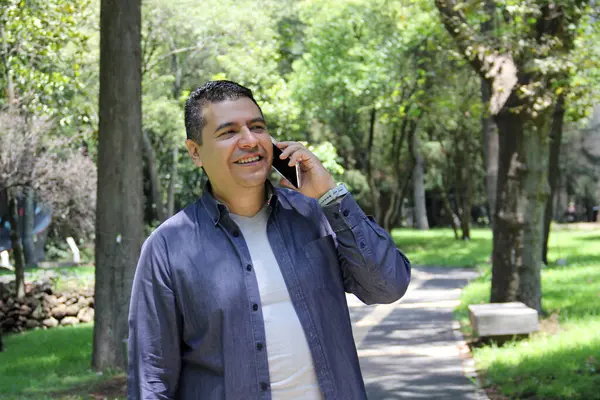 40-year-old dark-skinned Latino man walks while using his cell phone to make video calls, send messages, make payments, shop and work remotely