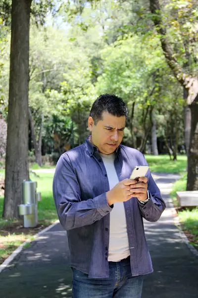 40-year-old dark-skinned Latino man walks while using his cell phone to make video calls, send messages, make payments, shop and work remotely