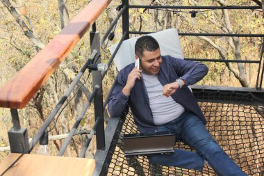 40 yaşındaki esmer tenli Latin adam bilgisayarını ve cep telefonunu dijital göçebe olarak kullanıyor. Ödemeler, alışverişler ve tarihler yapıyor.