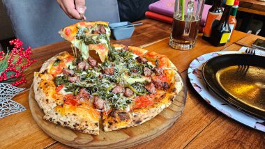 Domates soslu yuvarlak buğday unundan yapılmış pizza ve ahşap fırında pişirilmiş İtalyan sosisi.