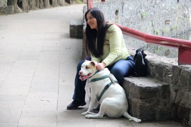 40 yaşındaki Latin bir kadın duygusal destek köpeğiyle parkta vakit geçirir ve ona duygusal ya da psikolojik zorluklar hakkında daha iyi hissetmesi için eşlik eder.