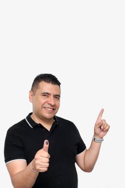 Latin yetişkin bir adam, özgür ve gizli oy hakkını kullandıktan sonra baş parmağını silinmez bir seçim mürekkebine buladı.