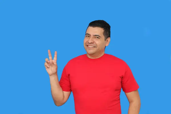 stock image Dark-skinned Latino adult man makes the victory sign with his fingers happy and excited